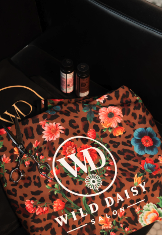 Wild Daisy Salon branded cape and tote folded on styling chair